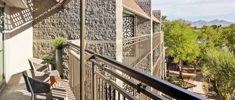A balcony with wicker furniture and a stone wall.