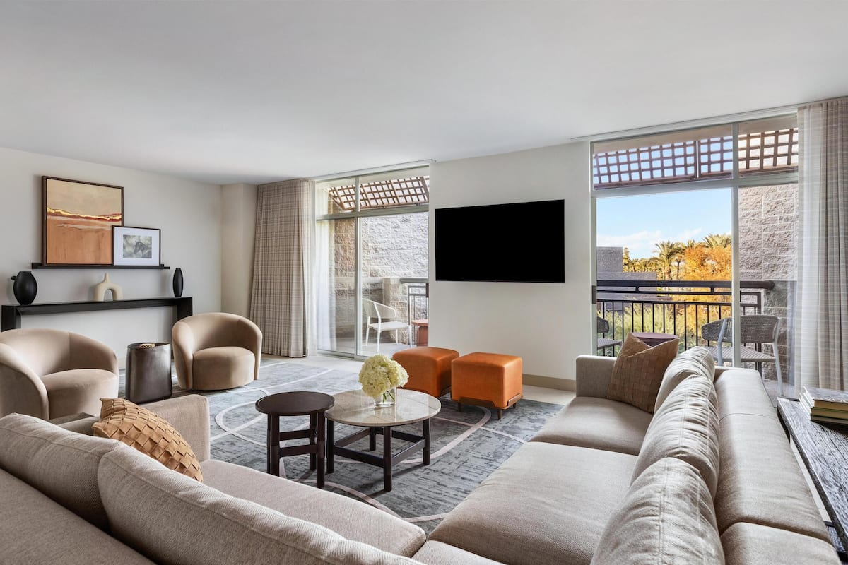 A modern living room with a sofa, armchairs, a coffee table, and a TV mounted on the wall.