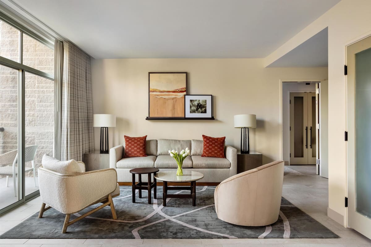 A modern living room with a sofa, armchairs, a coffee table, and artwork on the wall.