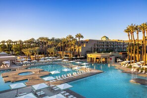 A resort with multiple swimming pools, sun loungers, and palm trees.