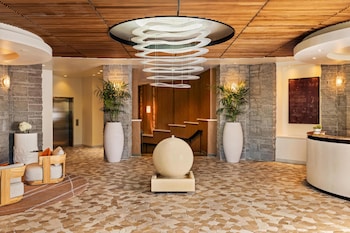 A hotel room with a bed, a sofa, a dining table, chairs, a lamp, a TV, and a view of the outdoor patio. at Grand Hyatt Scottsdale Resort