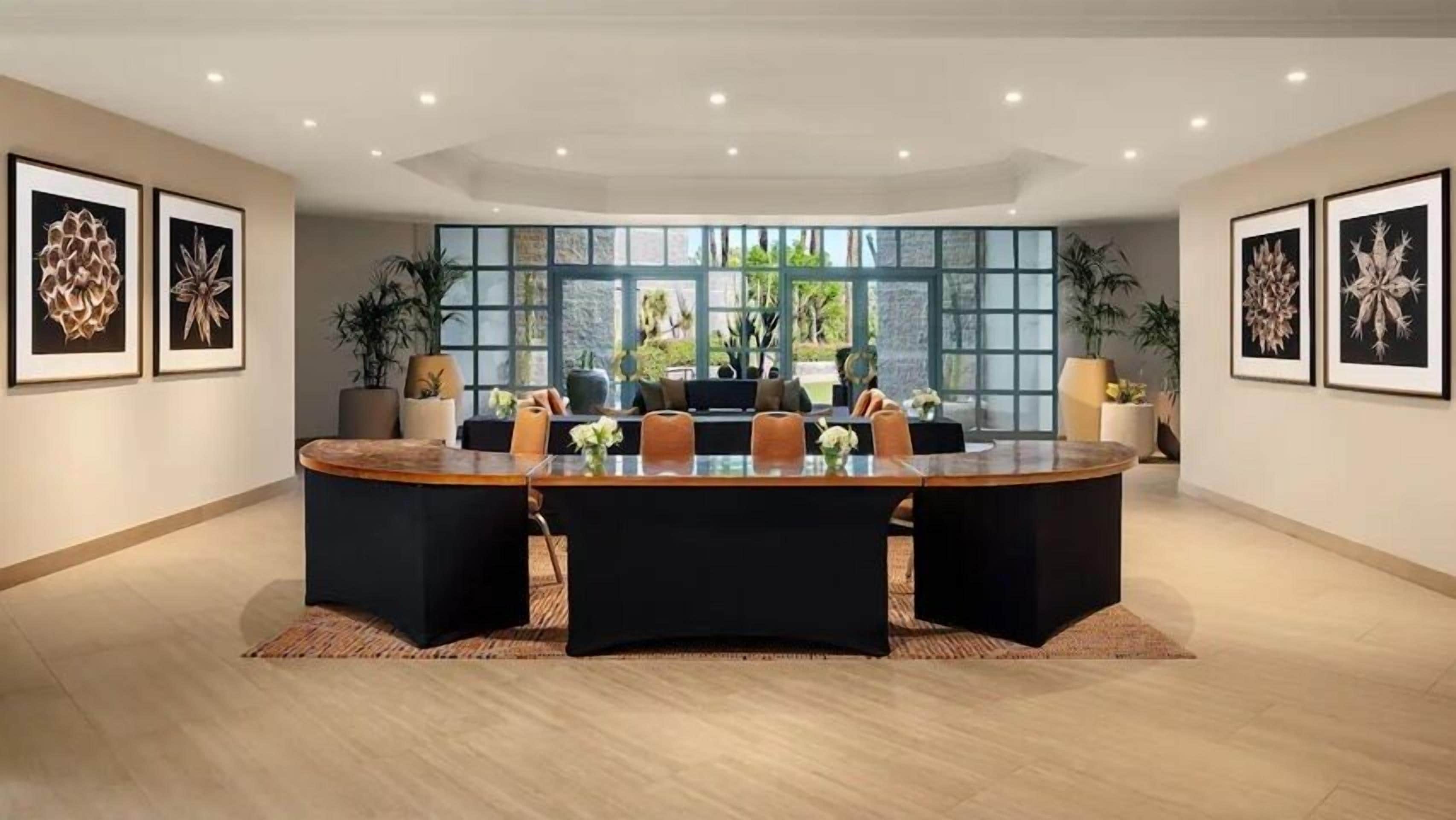 A conference room with a large oval table, black chairs, and framed botanical artwork on the walls.