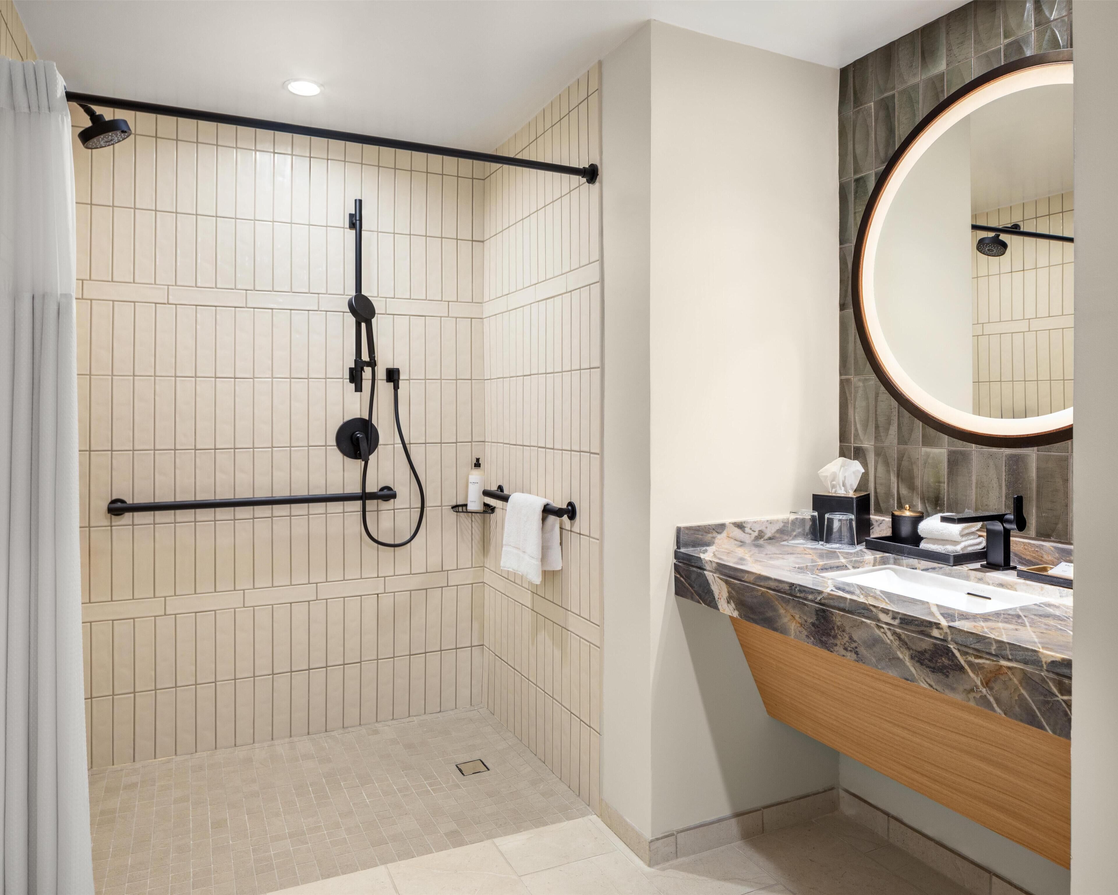 A modern bathroom with a shower, vanity, and a large mirror.