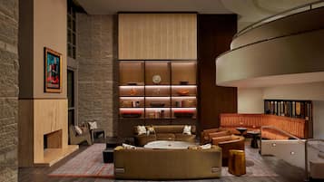 A modern interior with a fireplace, a sectional sofa, a round coffee table, and a built-in bookshelf with decorative items.
