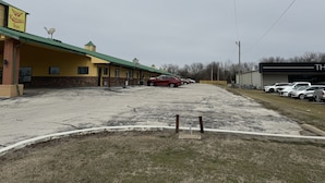 Un motel con techo verde y estacionamiento.