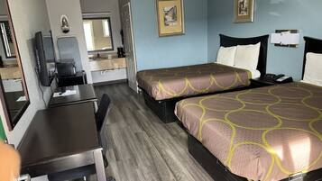 A hotel room with two beds, a desk, a chair, a desk lamp, a telephone, and a mirror.