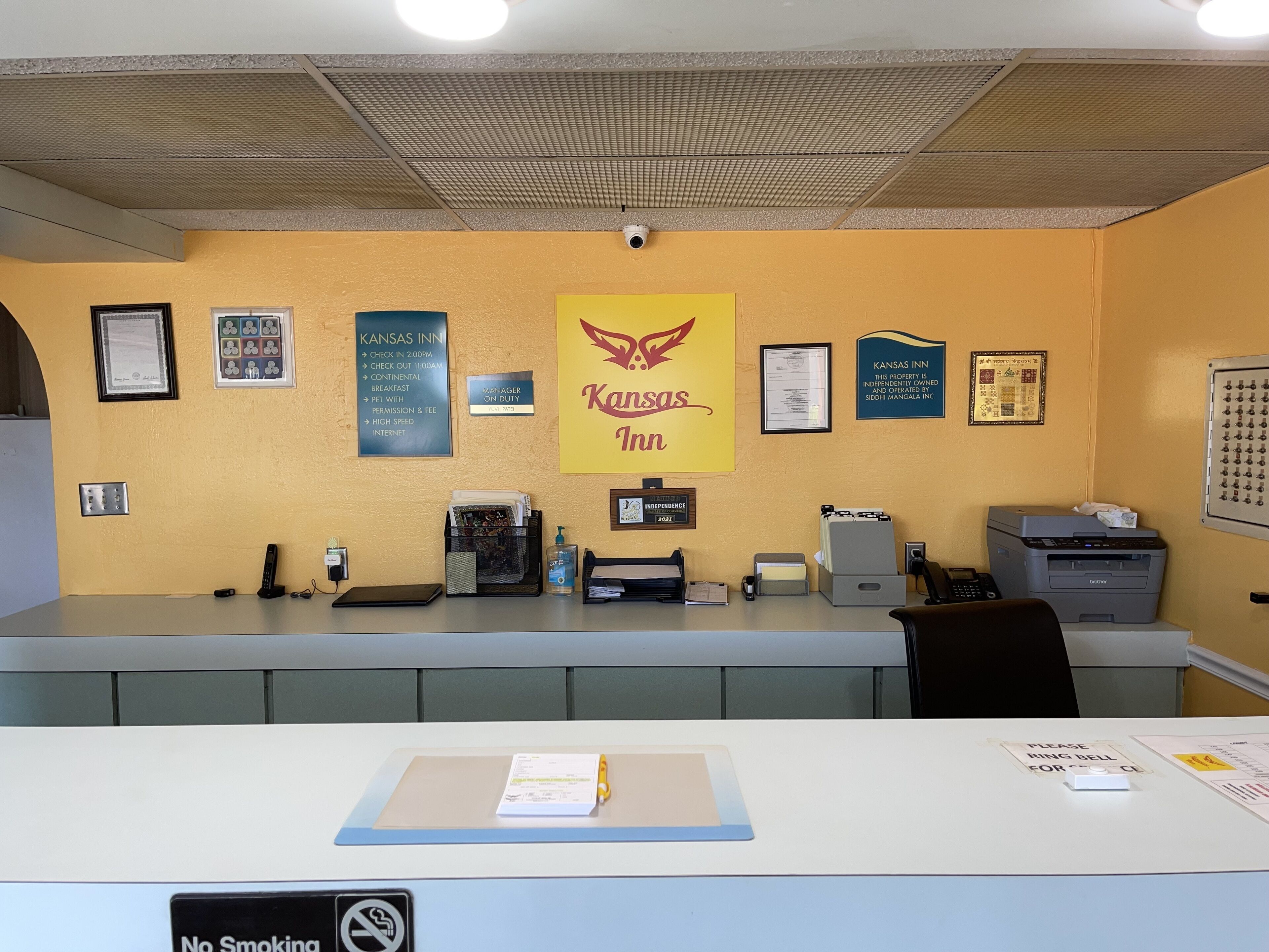 A reception desk with a sign for Kansas Inn, a no-smoking sign, and various office equipment.