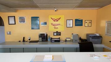 A reception desk with a sign for Kansas Inn, a no-smoking sign, and various office equipment.