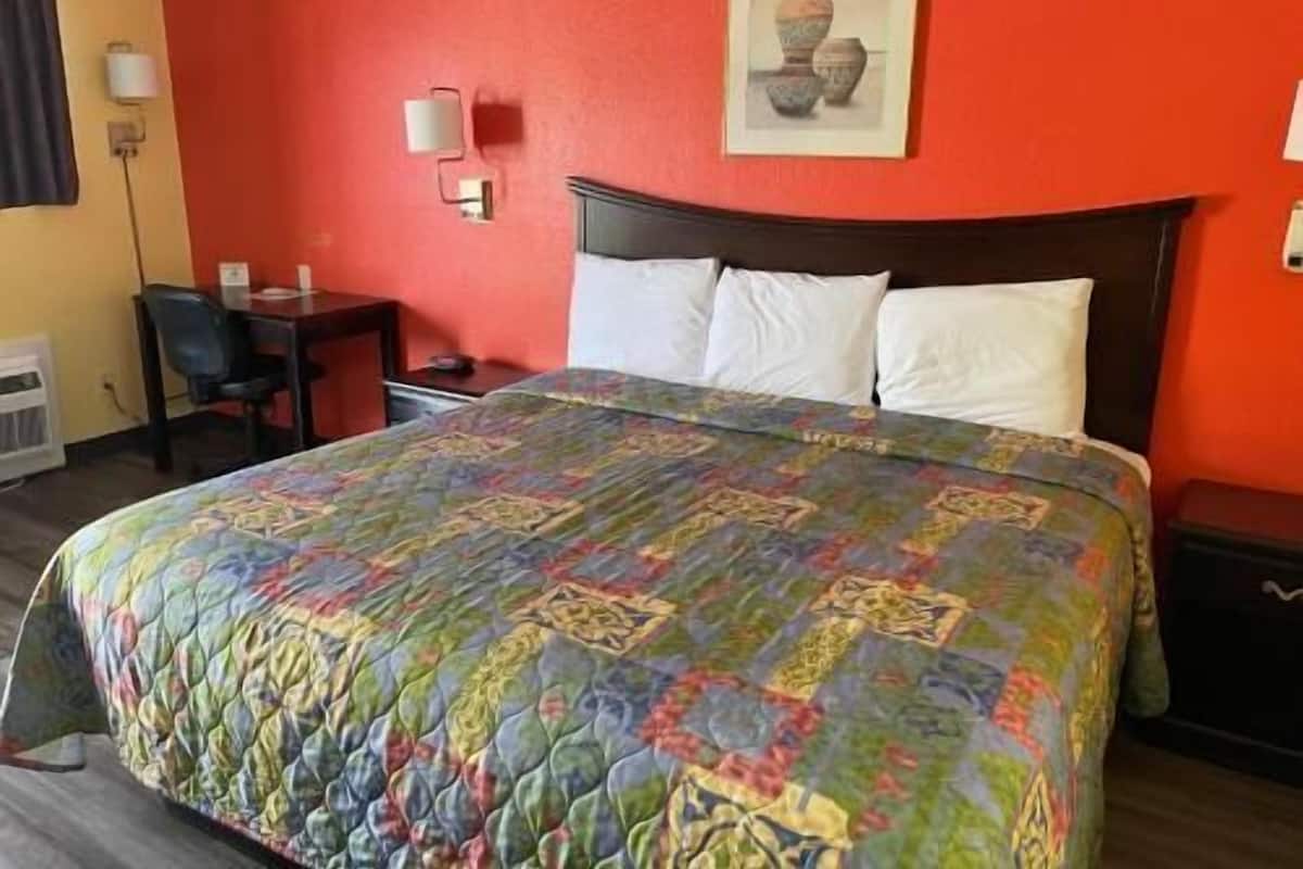 A hotel room with a bed, a desk, and a chair.