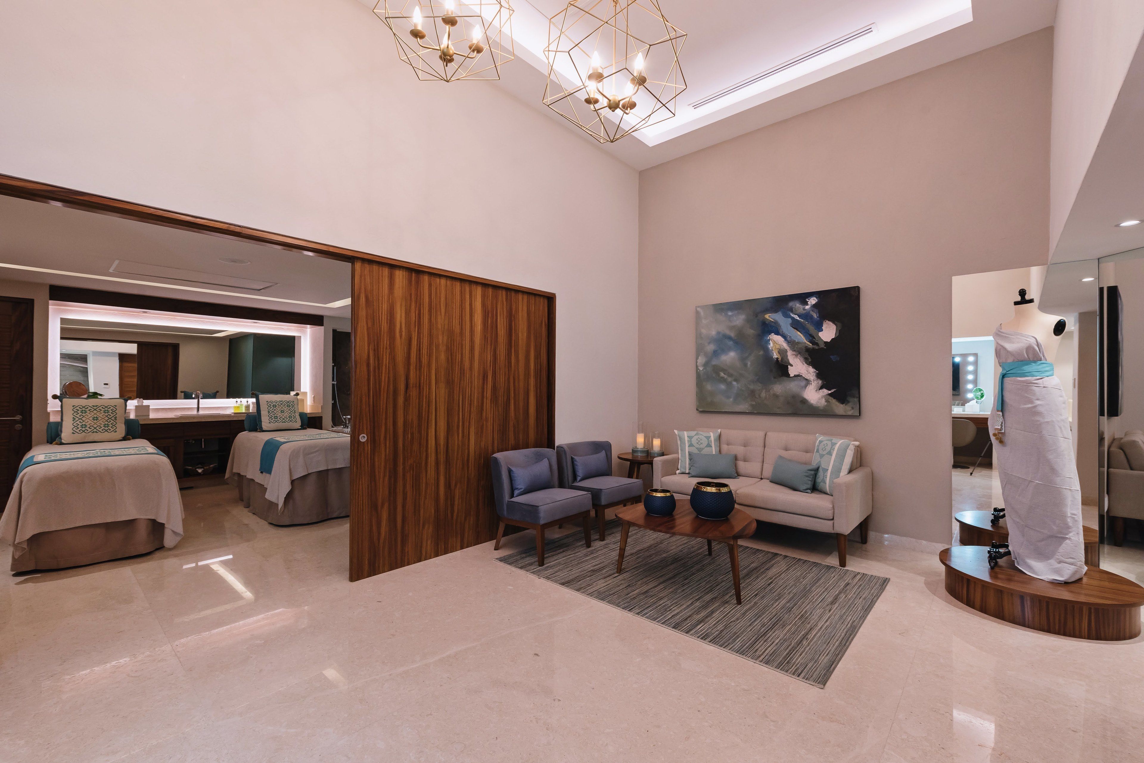 A modern hotel room with a large bed, a seating area with a sofa and chairs, a coffee table, and a large painting on the wall.