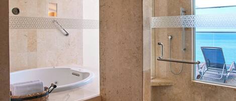 Un baño con bañera, ducha y ventana con vista al mar.