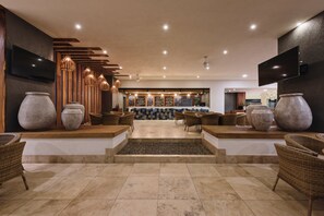 Un hall d’entrée spacieux avec un espace salon central, de grands vases et un design de plafond moderne.