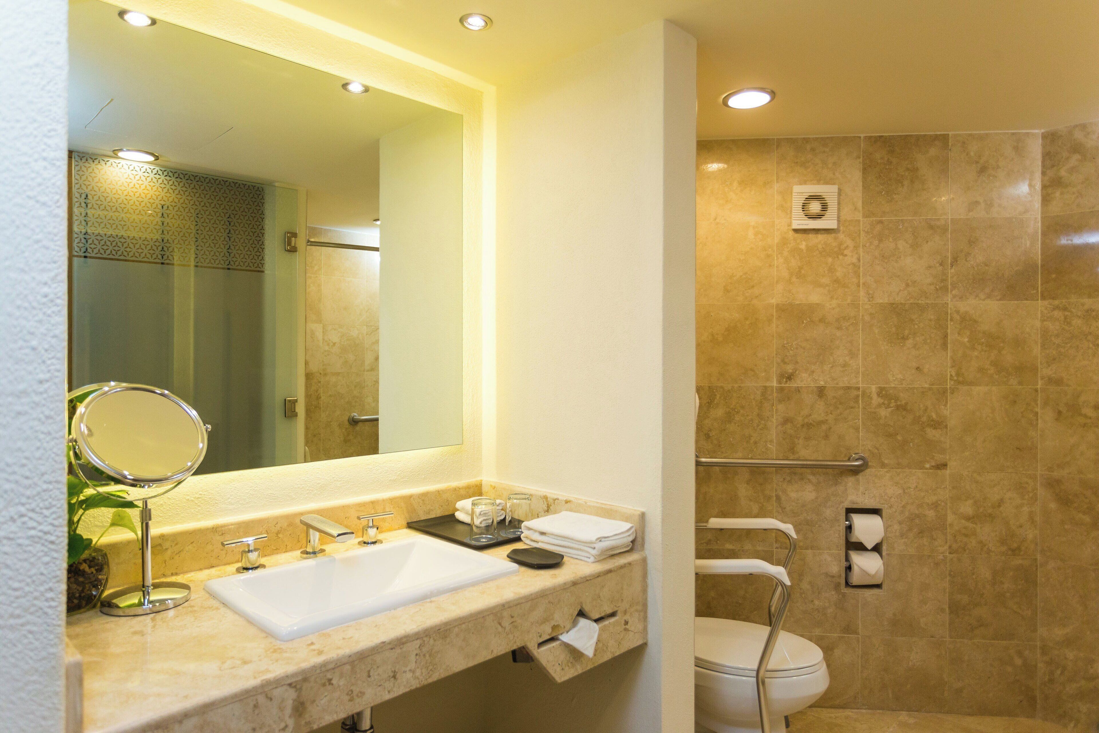 Een moderne badkamer met een grote spiegel, wastafel en douche.