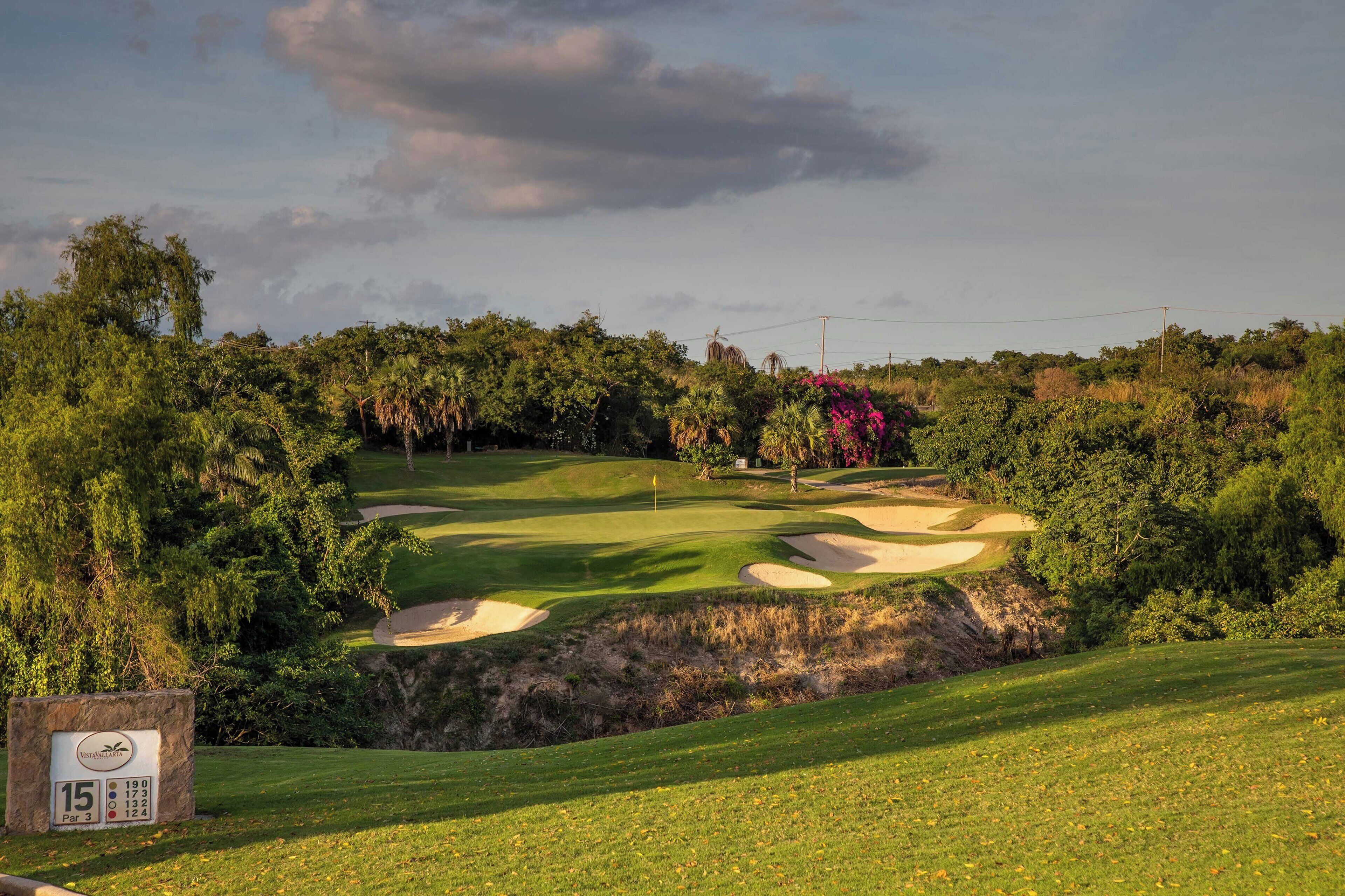 A golf course with sand bunkers, a flagstick, and a sign indicating a par 3 hole.