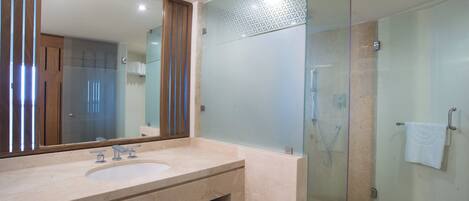 A modern bathroom with a glass-enclosed shower, a large mirror, and a marble sink.