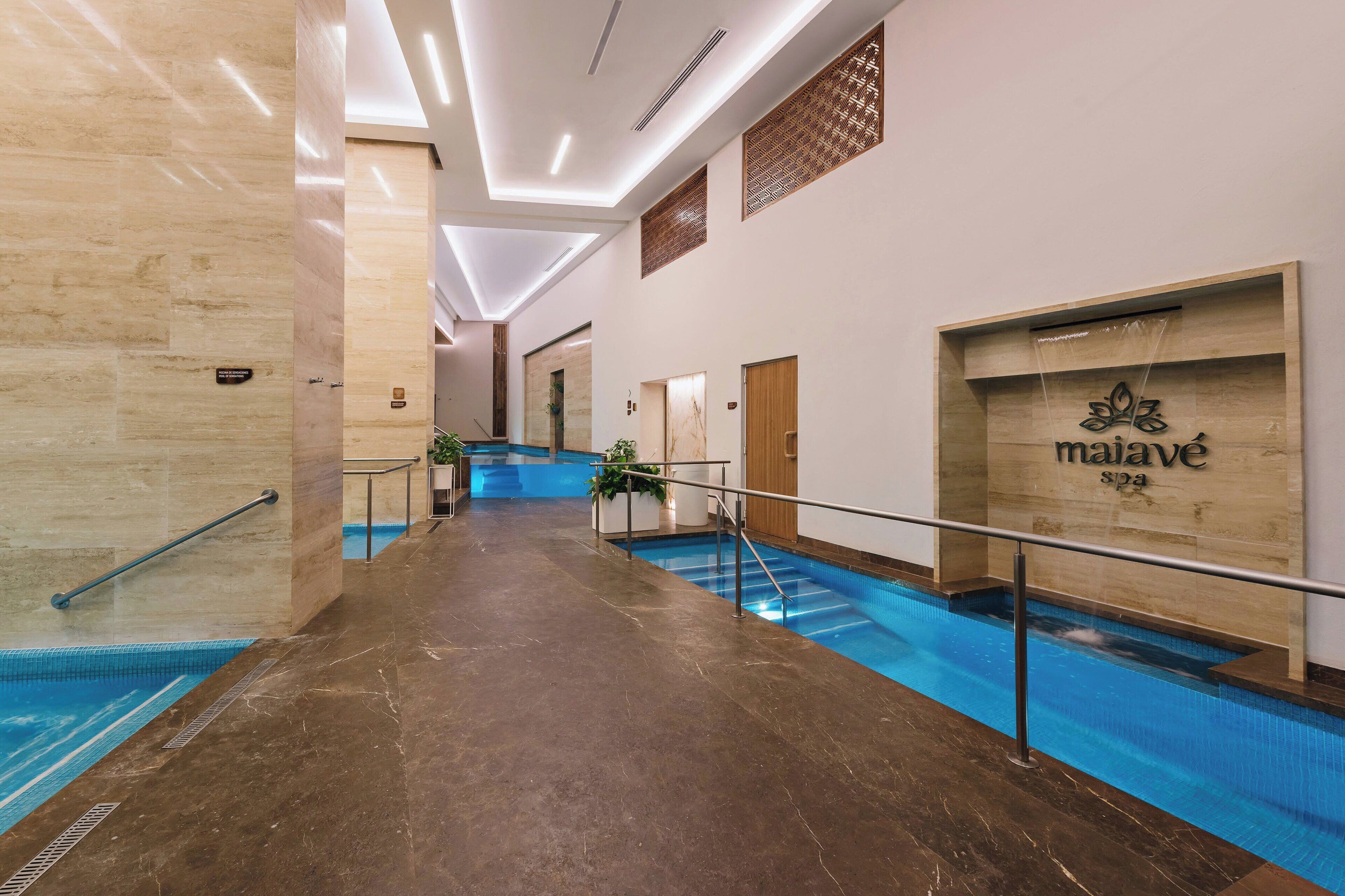 A hotel lobby with a marble floor, a pool area, and a spa sign.