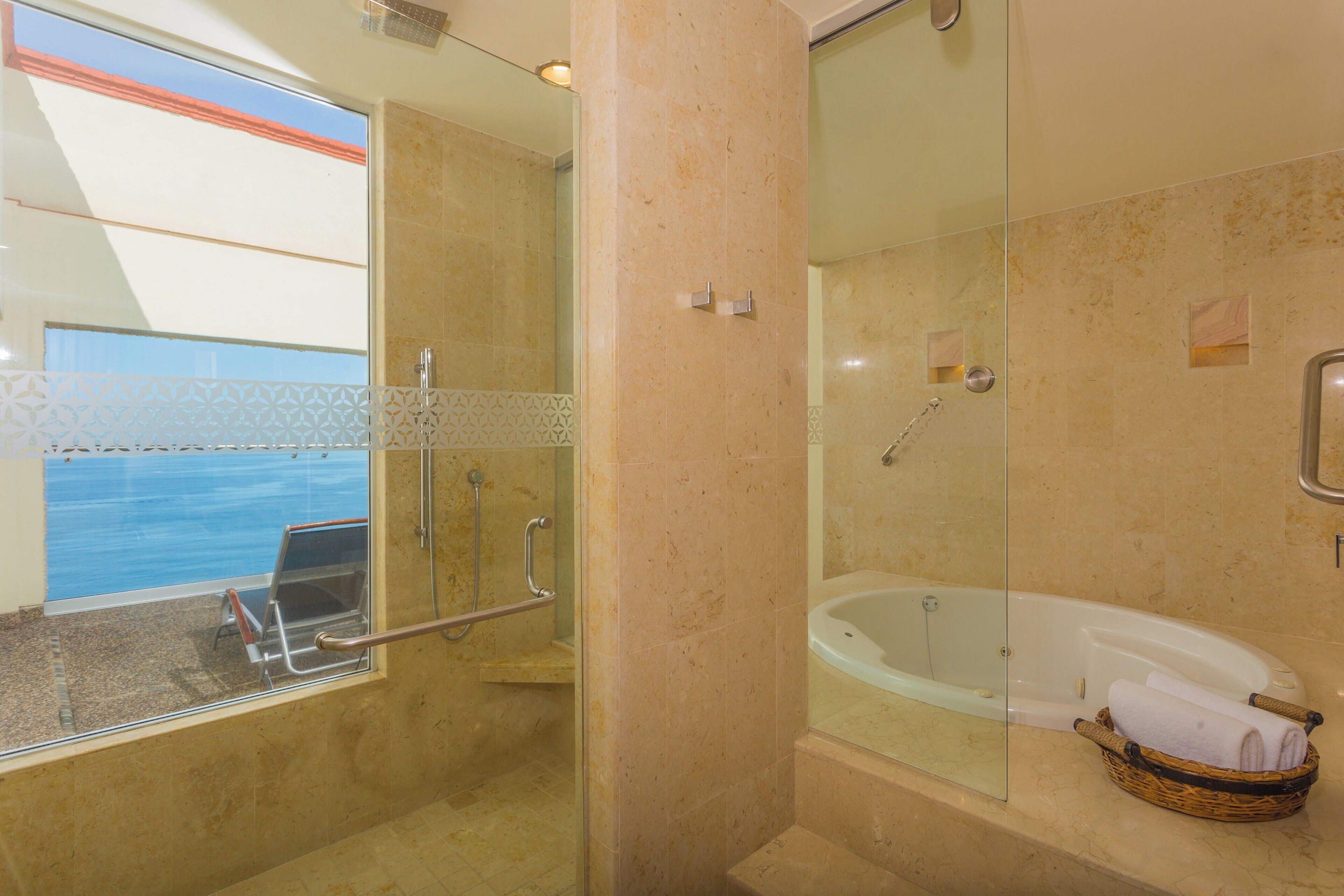A modern bathroom with a glass-enclosed shower, a bathtub, and a window overlooking a pool.
