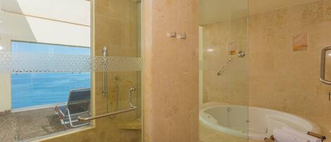 A modern bathroom with a glass-enclosed shower, a bathtub, and a window overlooking a pool.