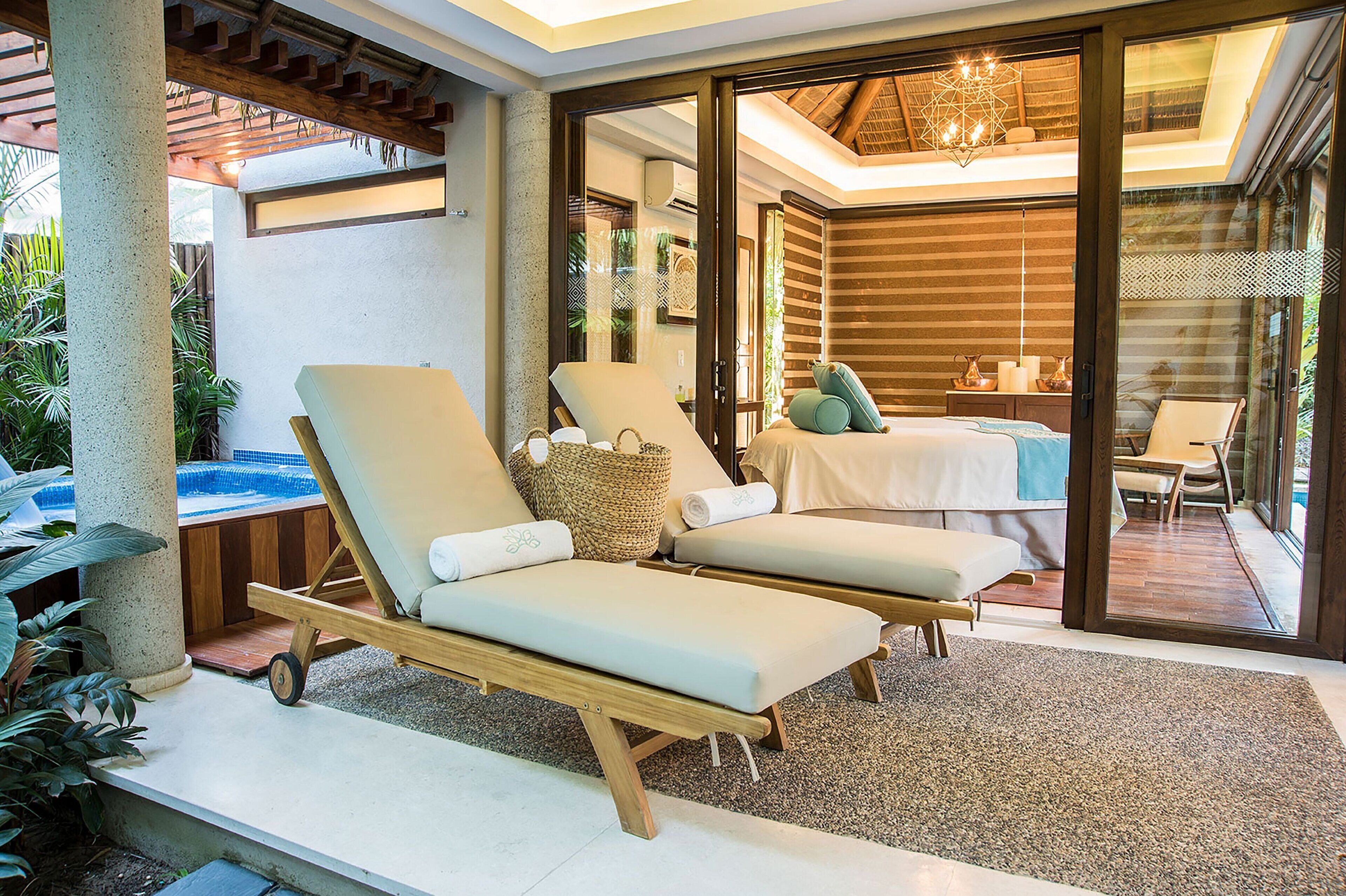 Un espace de détente extérieur moderne, comprenant deux chaises longues, une petite table et un jacuzzi.