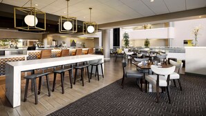 A modern hotel lobby with a central bar area, seating arrangements, and a patterned carpet. - Hilton Tucson East (Tucson)