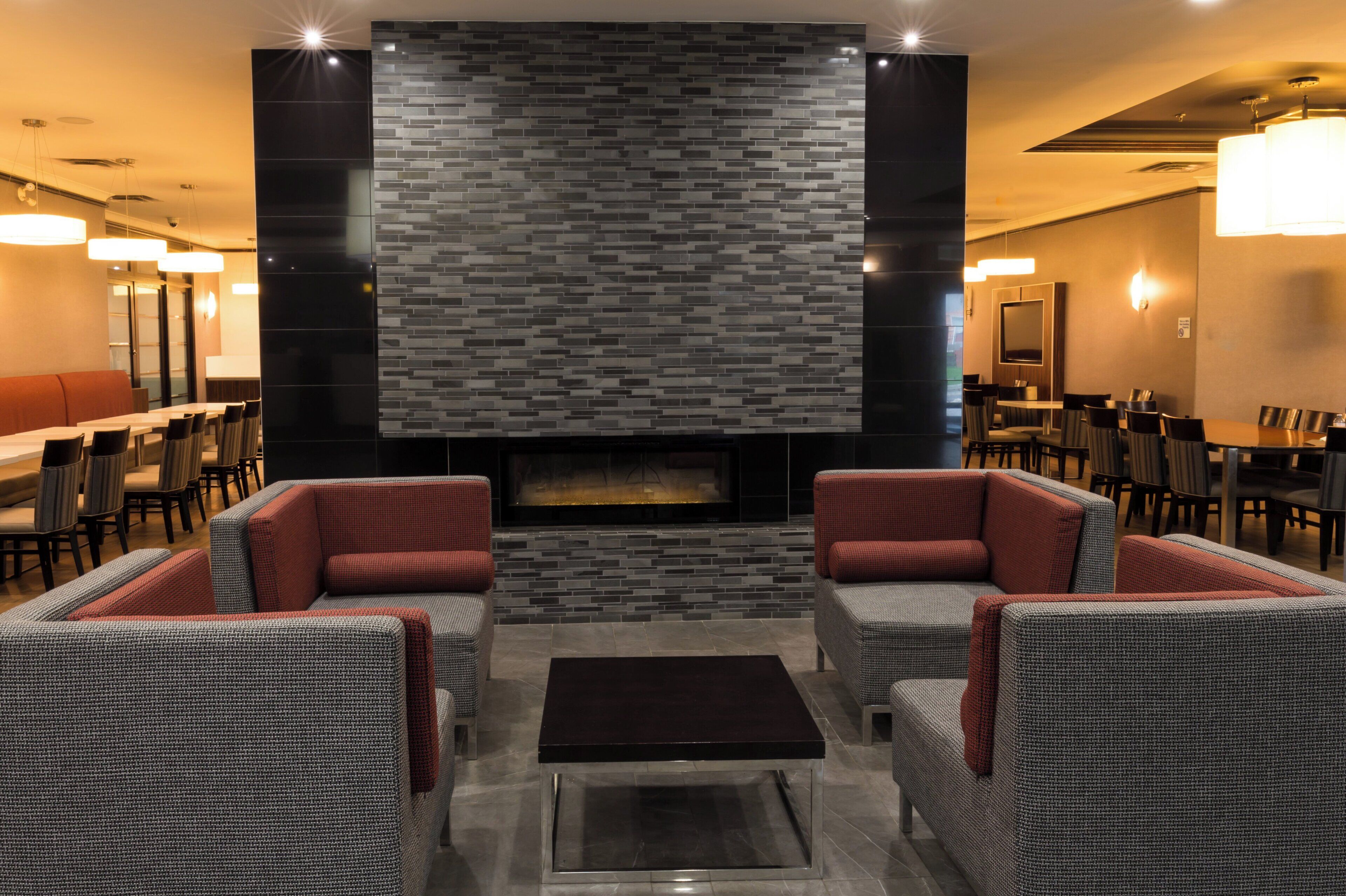 A modern lounge area with a fireplace, seating, and a dining area.