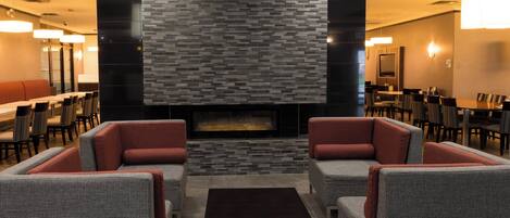 A modern lounge area with a fireplace, seating, and a dining area.