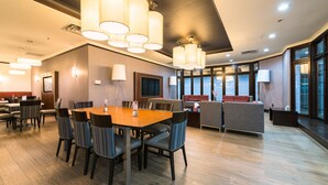 Un moderno vestíbulo de hotel con comedor, zonas de estar y amplios ventanales que dejan entrar luz natural.