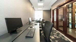 Un salón de conferencias con una larga mesa, varias sillas, una computadora y un amplio ventanal con cortinas.