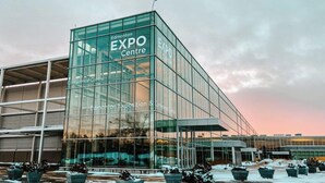 A modern glass building with "Edmonton Expo Centre" signage, featuring a large glass facade and a flat roof.