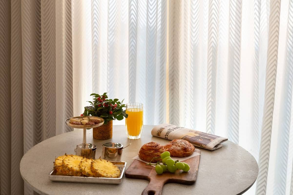 Ein Esstisch mit einer Ananas, einem Glas Orangensaft, einer Pflanze und einer Zeitung.