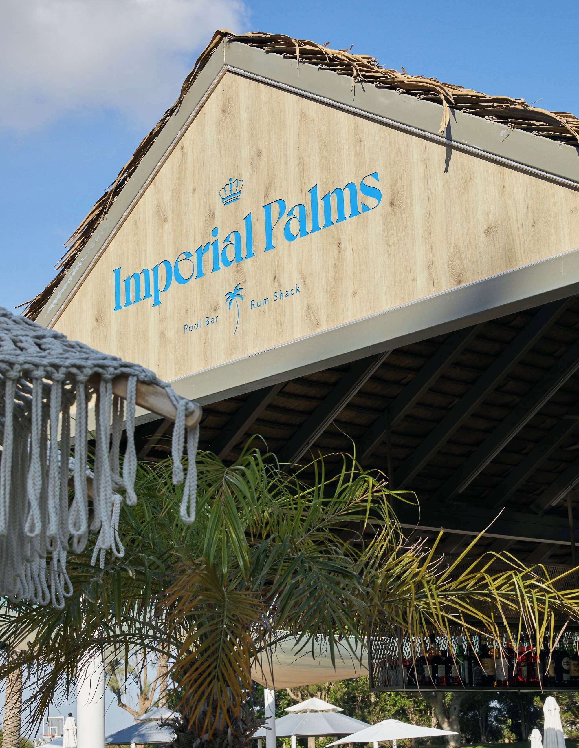 Exterior do Imperial Palms, com um letreiro indicando bar na piscina e bar de rum.