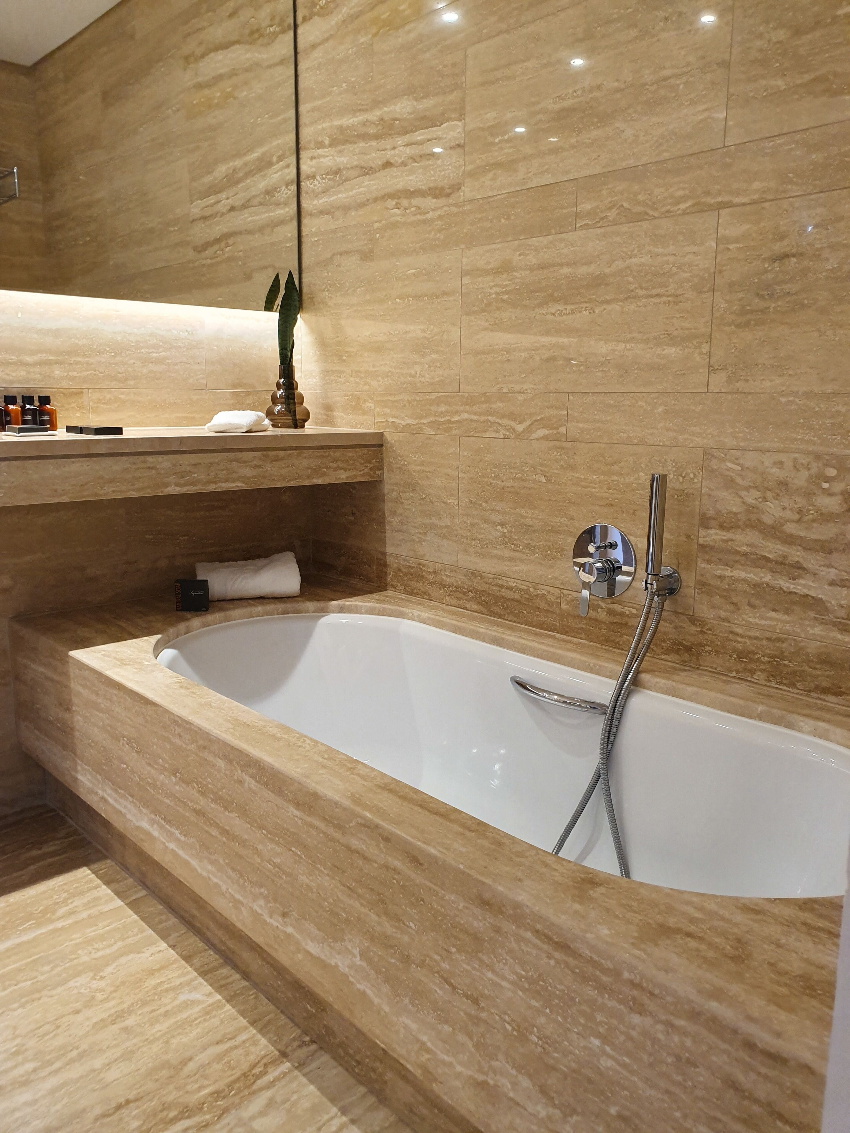 Un baño moderno con una bañera grande, un espejo y artículos de aseo en el mostrador.