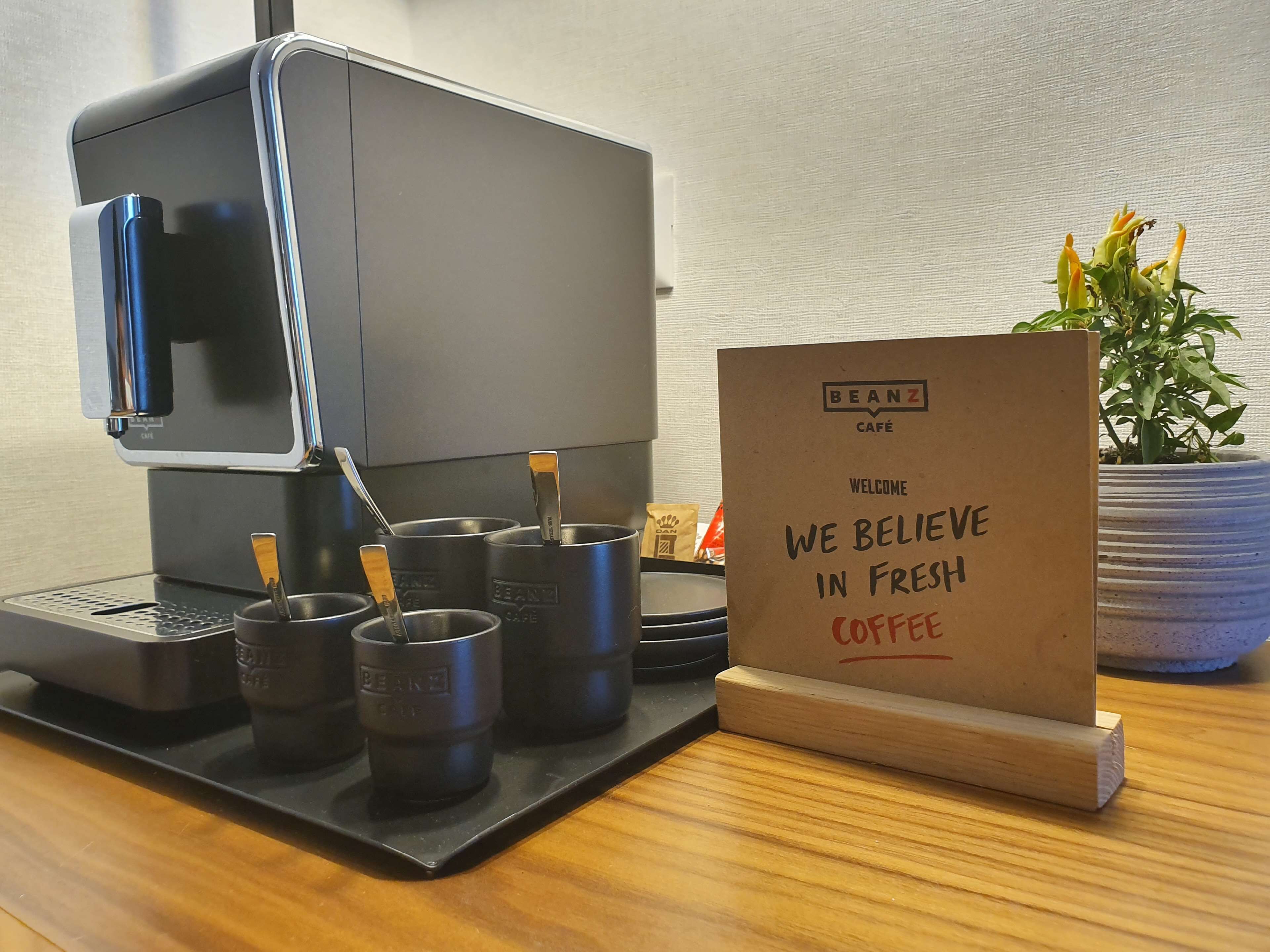 A coffee machine with cups and a sign that reads "BEANZ CAFE".