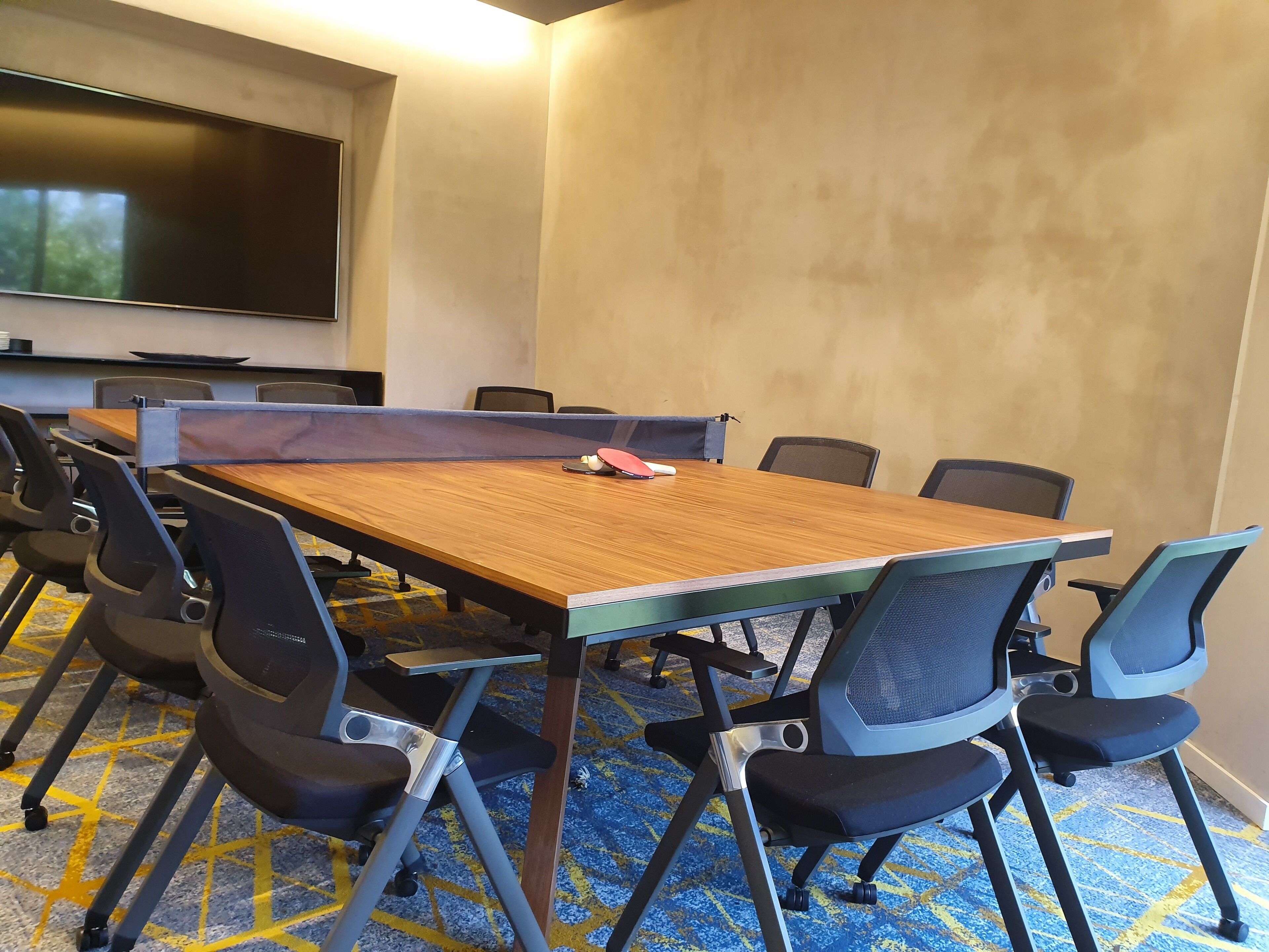 A conference room with a large table, chairs, and a flat-screen TV on the wall.