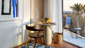Una habitación moderna con comedor que incluye una mesa redonda, una silla y vistas de la ciudad a través de ventanas amplias.