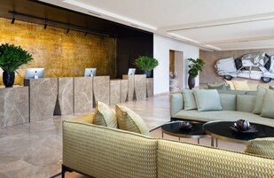 Un vestíbulo moderno con mostrador de recepción, zona de estar y una gran obra de arte en la pared.