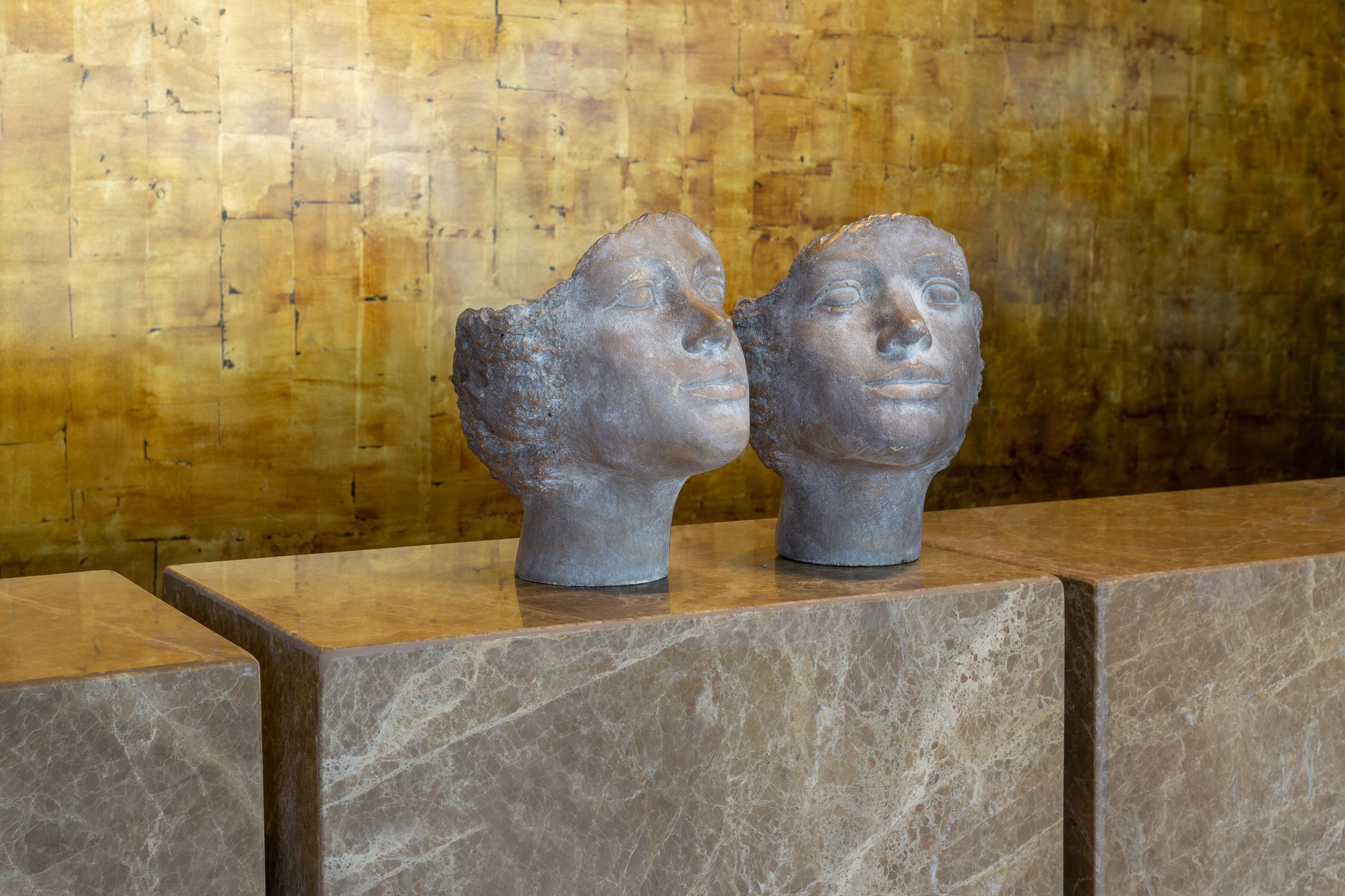 Two stone busts on a marble ledge against a wooden wall.