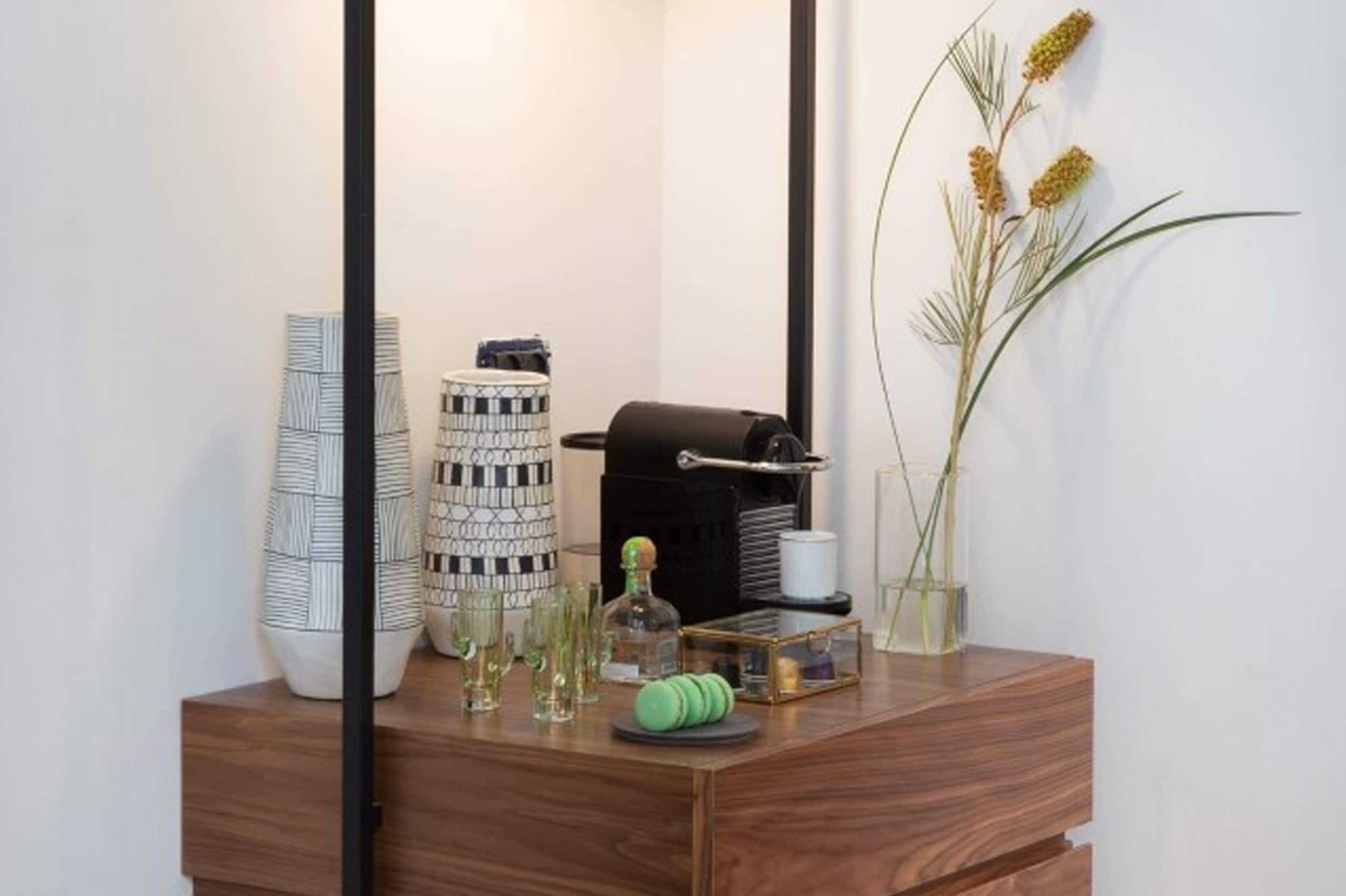 Un mobile bagno in legno con specchio, un asciugamano, una bottiglia e oggetti decorativi.