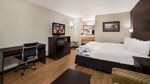 A hotel room with a bed, a desk with a chair, a television, a dresser, and a mirror.