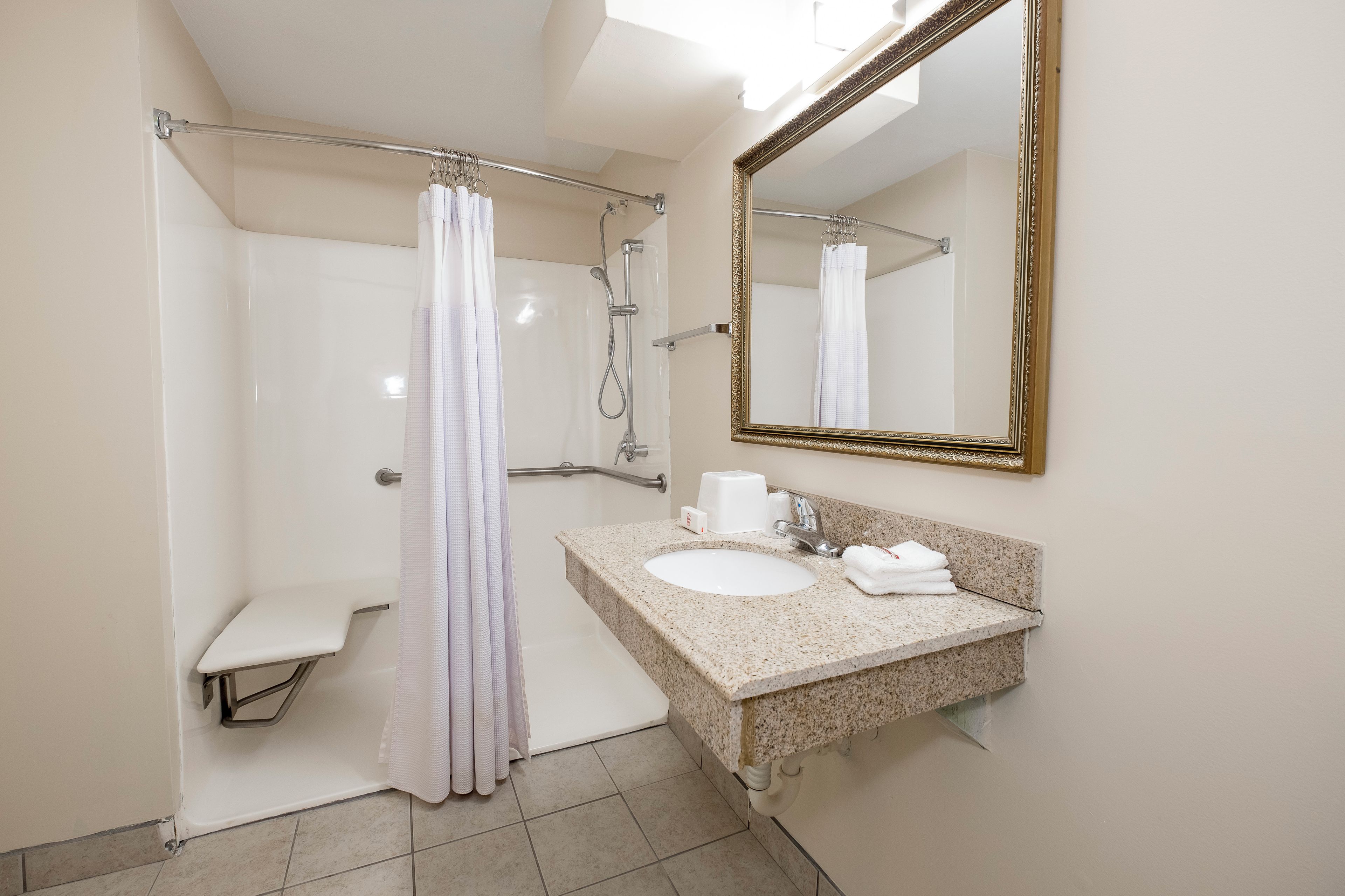 A bathroom with a shower, a sink, a toilet, and a mirror.