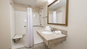 A bathroom with a shower, a sink, a toilet, and a mirror.