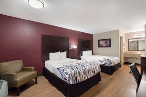 Habitación de hotel con dos camas, un escritorio, una silla, un espejo y un cuadro en la pared.