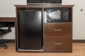 Una kitchenette compacta con refrigerador, microondas y un pequeño armario.