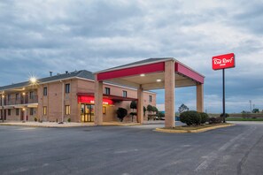 Un hôtel Red Roof Inn doté d’un parking couvert et offrant une vue sur un ciel dégagé.