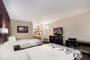 Une chambre d’hôtel avec deux lits, une télévision, un bureau et une chaise.