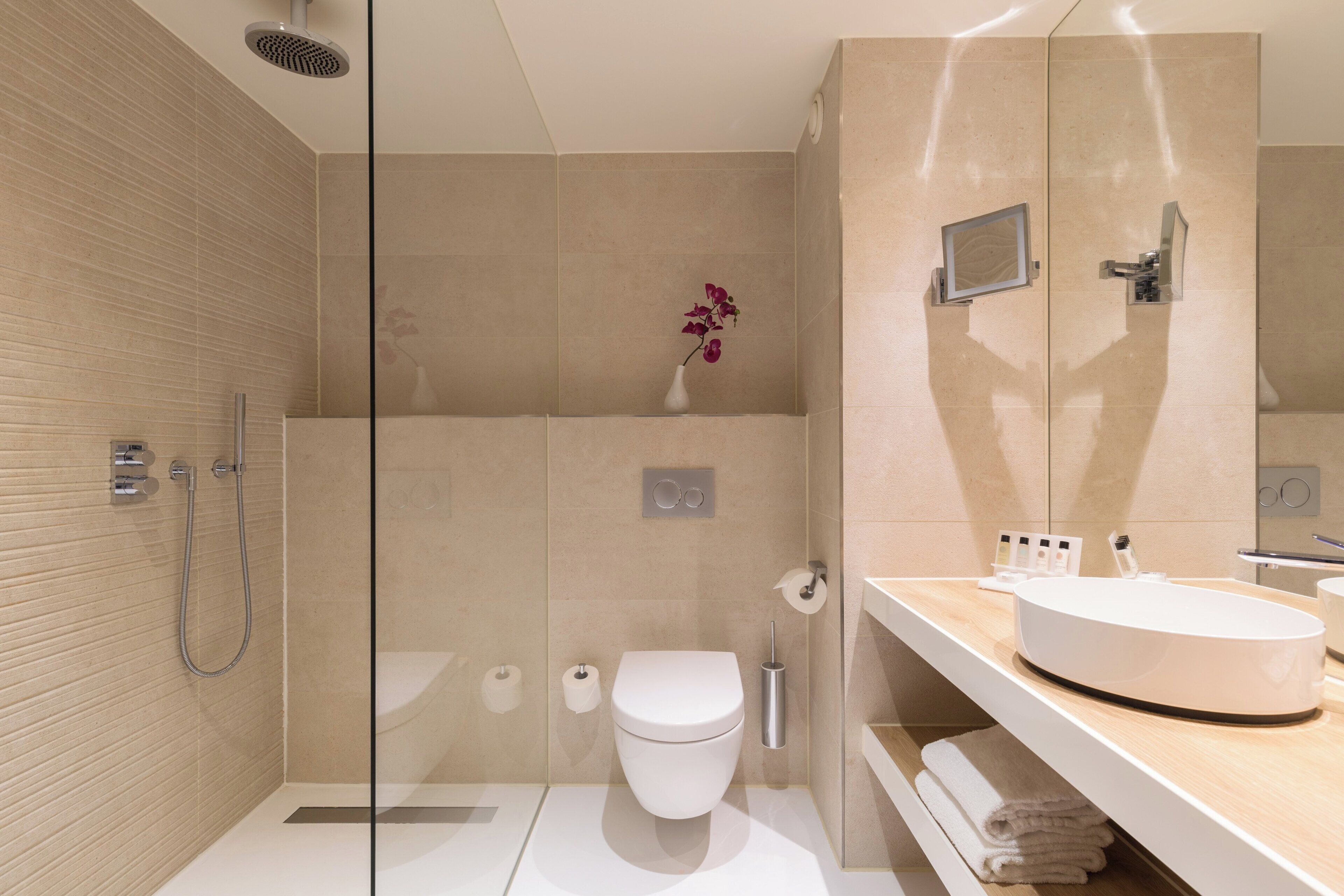 A modern bathroom with a glass shower enclosure, a white toilet, and a vanity with a sink and mirror.