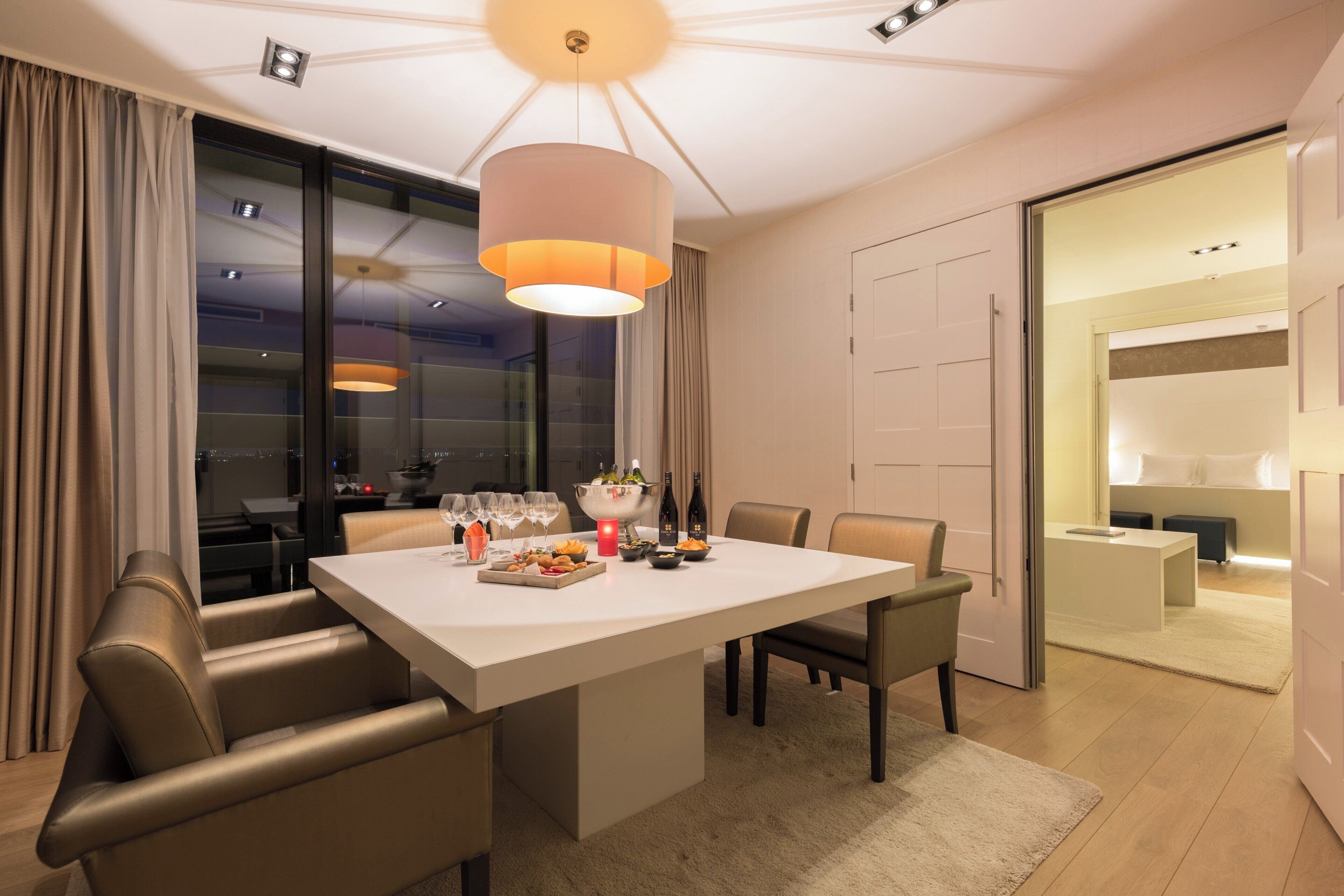 A modern dining area with a large table, comfortable seating, and a chandelier.