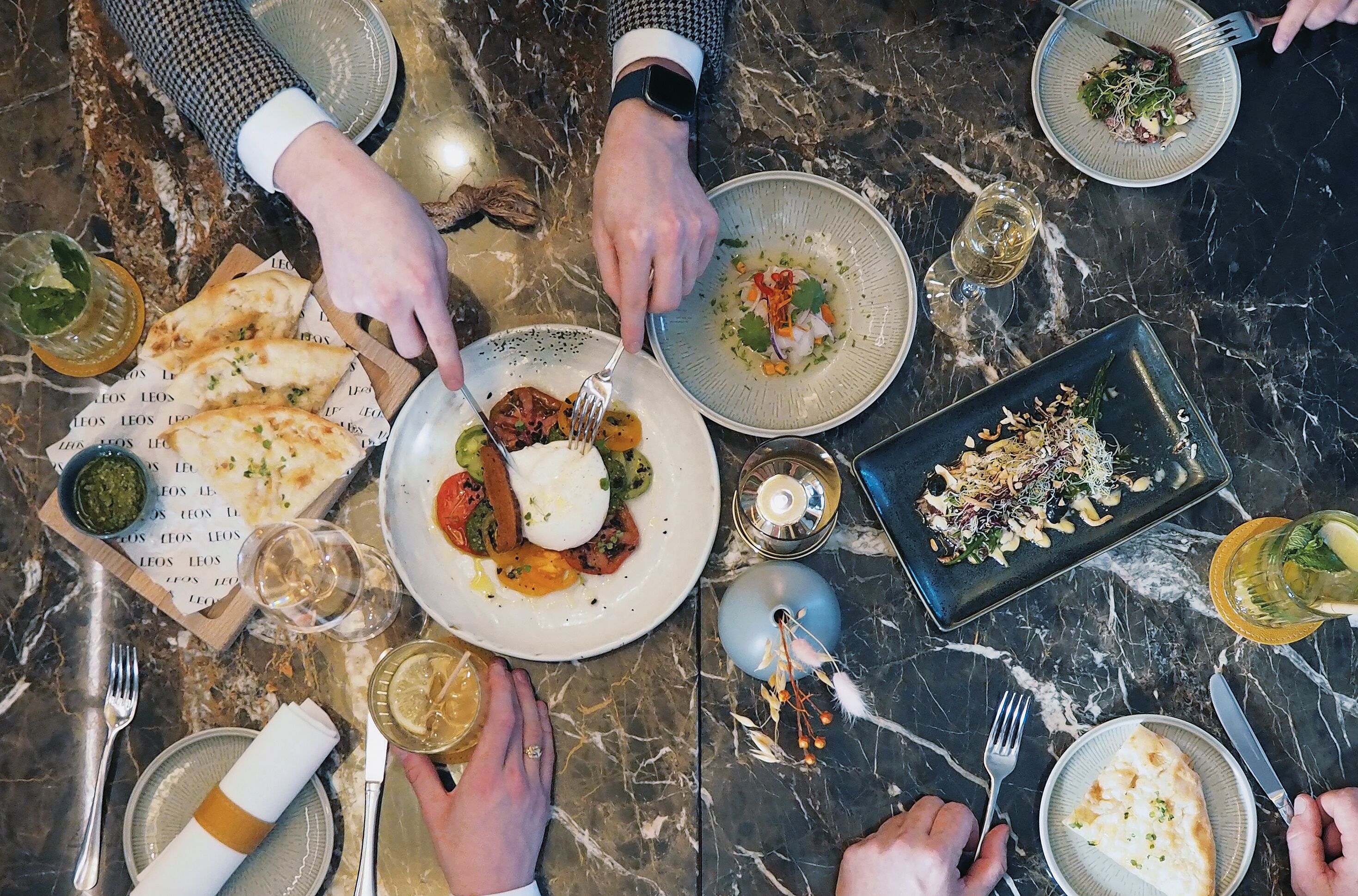 Une table à manger avec de nombreuses assiettes remplies de nourriture, des couverts et des verres de vin.