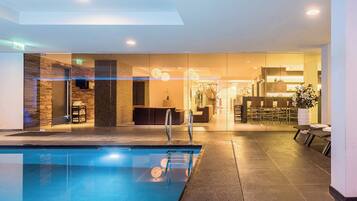 Una piscina techada, sillones reclinables de piscina