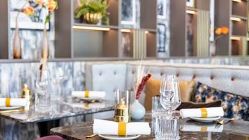 Un espace repas avec des tables en marbre, élégamment dressées avec des assiettes, des verres et des bougies.